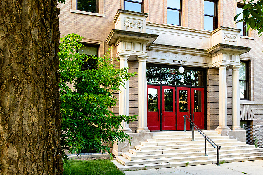 Stairs leading up to Education building entrance furnished with bright red doors and ornate pillars.
